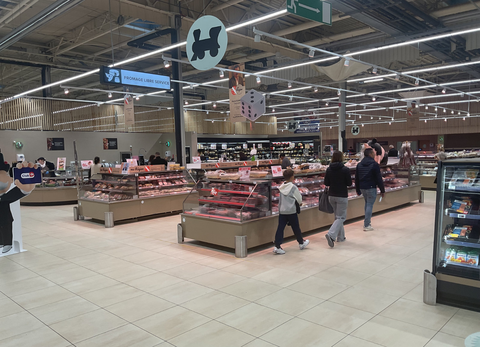 Rayon boucherie en grande surface avec vitrines réfrigérées et clients, aménagement commercial Carrefour