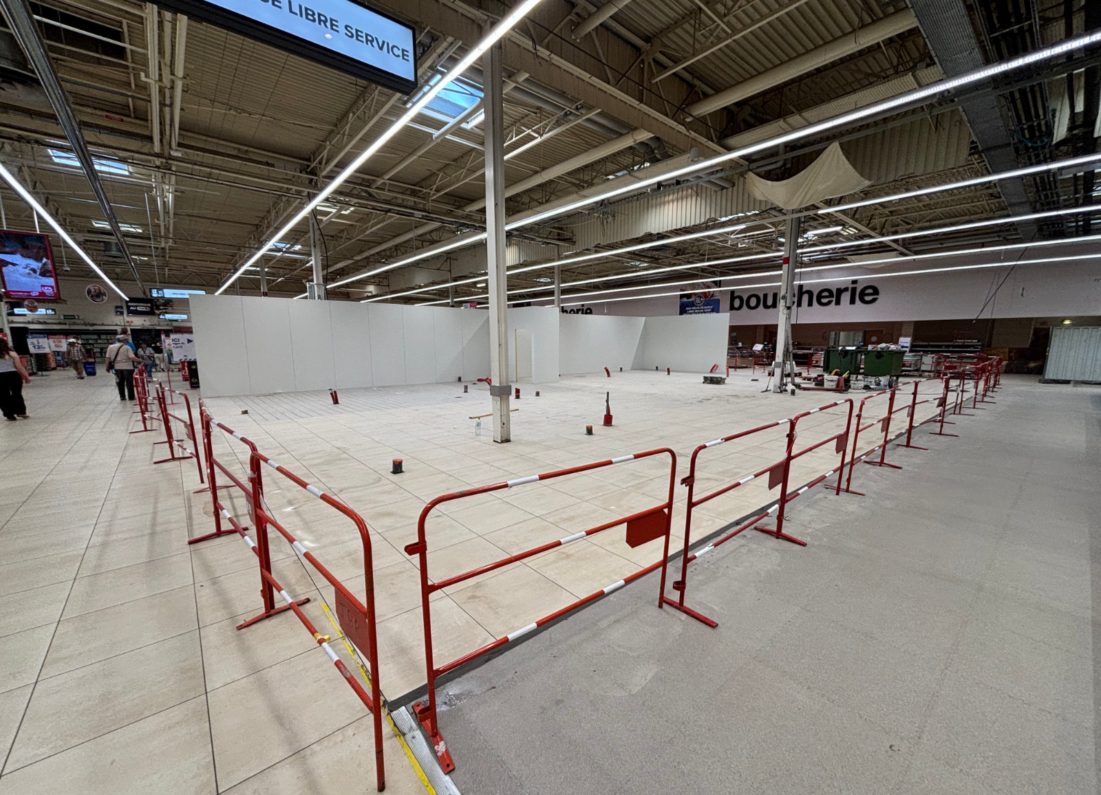 Zone de travaux en grande surface avec balisage de chantier, réaménagement intérieur en magasin