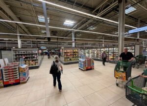 Allée de circulation en grande surface avec rayons alimentaires et clients, optimisation des flux en magasin