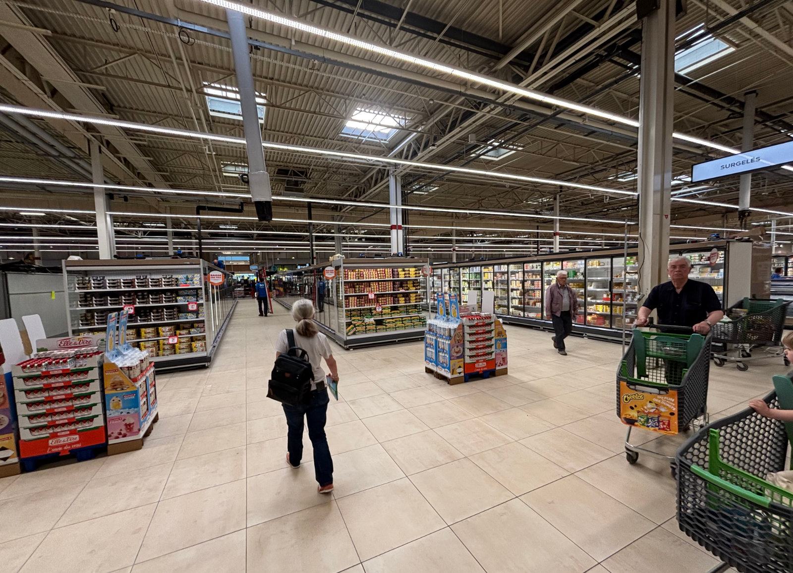 Allée de circulation en grande surface avec rayons alimentaires et clients, optimisation des flux en magasin