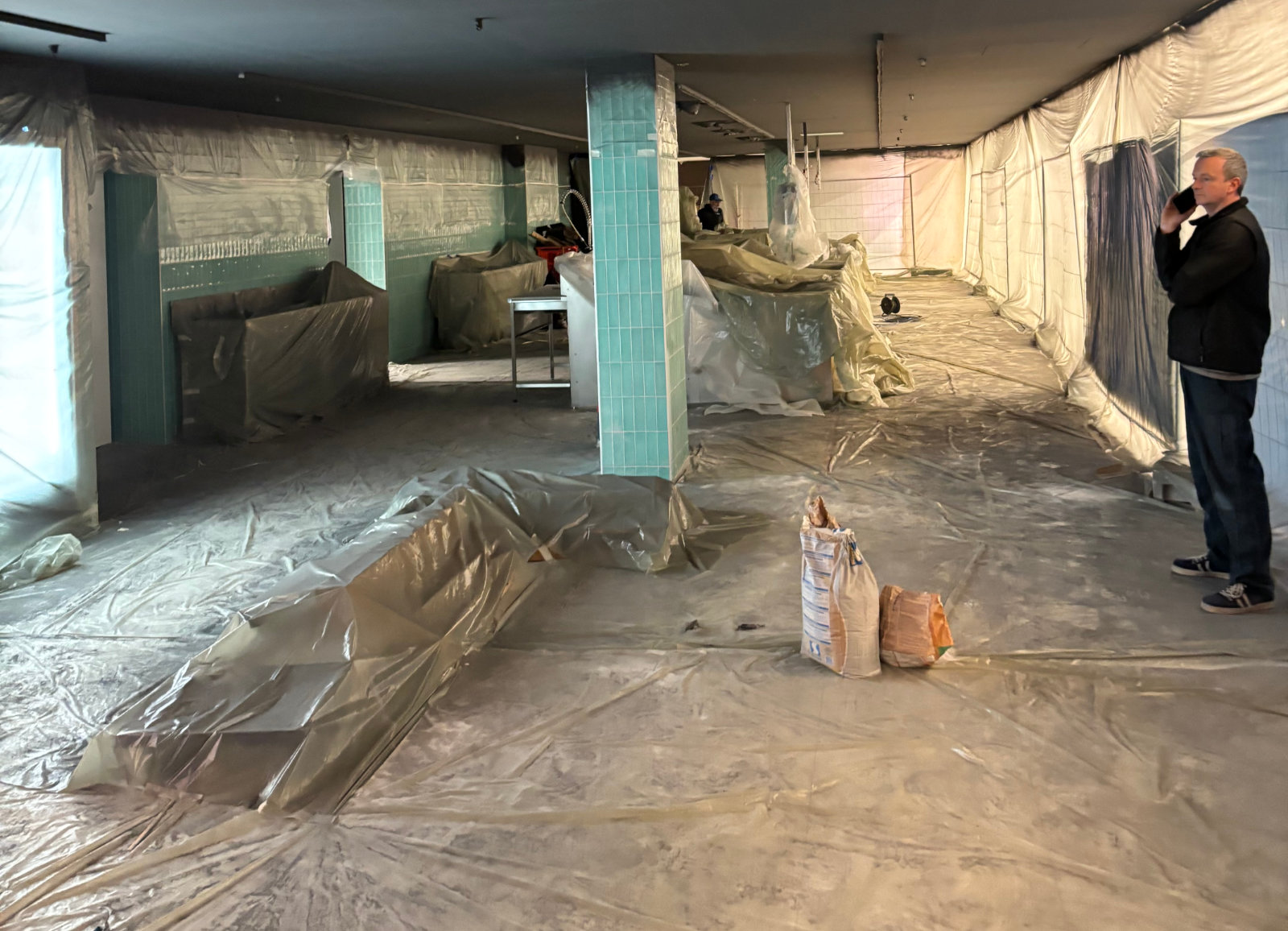 Zone de travaux confinée avec protection plastique pour rénovation intérieure en grande surface